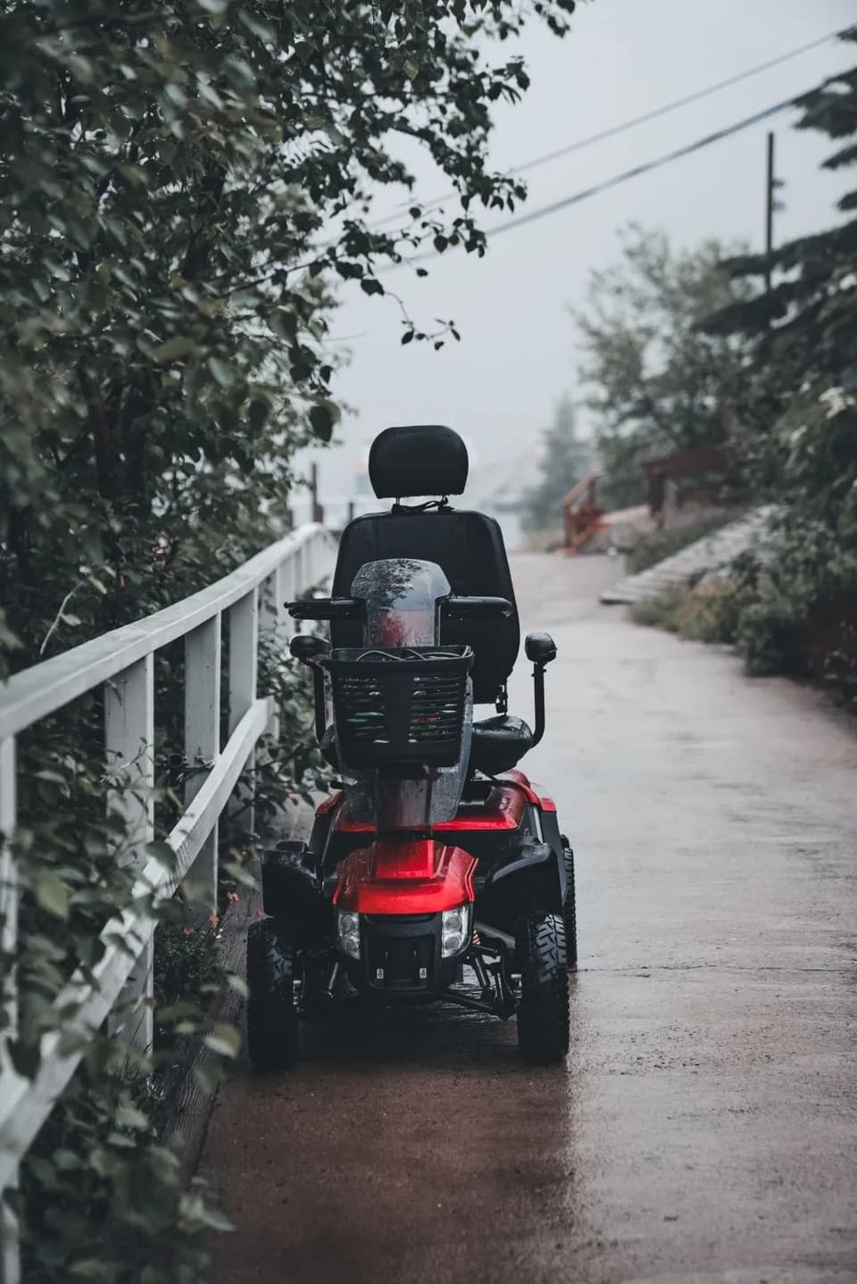 A red four-wheel mobility scooter parked on an accessible paved path